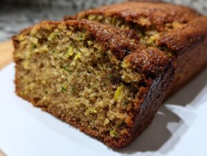Close-up of a moist slice of banana zucchini bread showing the tender crumb and flecks of green zucchini.
