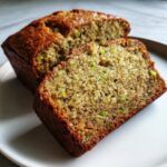Close-up of moist banana zucchini bread, showing the texture with visible green zucchini shreds and dark specks.