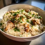 Close-up of creamy one pot chicken and rice topped with shredded cheese and fresh parsley.