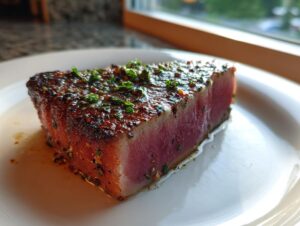 A thick, perfectly seared tuna steak, rare in the center, topped with a glistening herb and spice crust.