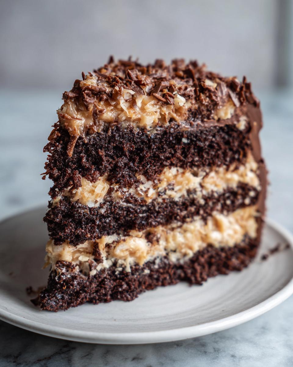 Close-up of a decadent slice of German chocolate cake showing dark chocolate layers and coconut-pecan frosting.
