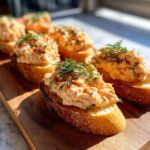 Several smoked salmon bites served on toasted baguette slices, garnished with fresh dill, ready to eat.