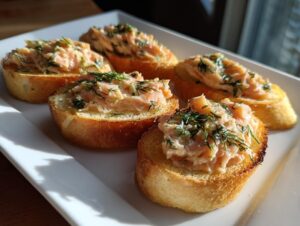 Five delicious smoked salmon bites served on toasted baguette slices and garnished with fresh dill.