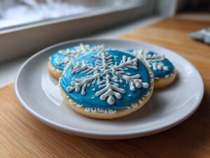 Three round sugar cookies decorated with vibrant blue cookie icing and white snowflake designs.