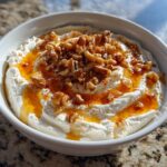 A white bowl filled with creamy whipped ricotta dip, drizzled with honey and topped with chopped walnuts.