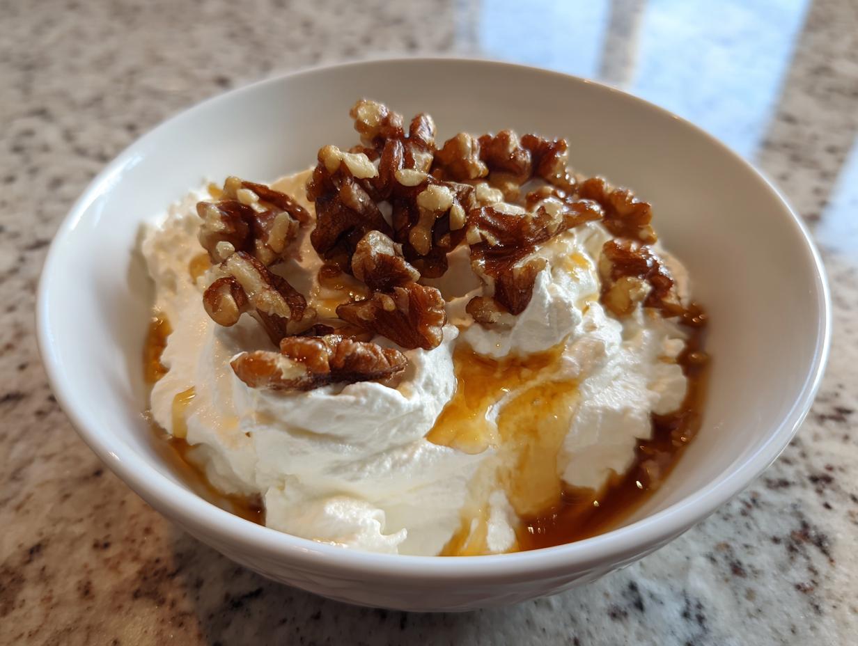 Close-up of a bowl of creamy whipped ricotta dip topped with candied walnuts and drizzled with honey.