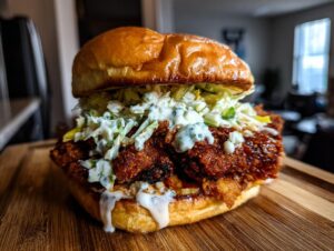 A close-up shot of an amazing buffalo chicken sandwich with crispy chicken, coleslaw, and blue cheese dressing on a brioche bun.