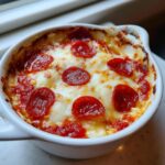 Close-up of a baked cottage cheese pizza bowl topped with melted mozzarella and pepperoni slices.