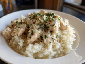 Close-up of tender chicken scampi pieces served over creamy garlic parmesan rice and topped with fresh parsley.