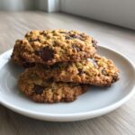 A stack of three delicious, textured chocolate chip zucchini cookies resting on a small white plate.