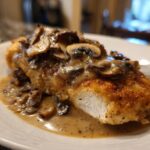 A close-up of a breaded chicken breast smothered in creamy mushroom sauce, showcasing the perfect chicken marsala.