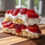 Close-up of a delicious slice of shortcake layered with macerated strawberries and whipped cream.