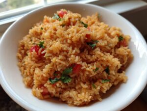 Close-up of fluffy spanish rice mixed with diced tomatoes and cilantro in a white bowl.