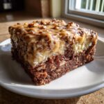Close-up of a rich slice of german chocolate poke cake with coconut-pecan frosting.