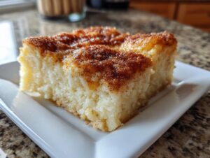 A close-up of a gooey slice of amazing snickerdoodle cobbler topped with cinnamon sugar.