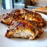 Close-up of juicy, browned chicken thighs seasoned with herbs, showing the interior texture after using the best chicken marinade.