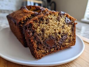 Close-up of a thick slice of moist chocolate chip banana bread showing melted chocolate pockets.