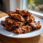 A pile of crispy, seasoned, shredded meat, perfect for homemade doner kebab, served on a white plate.