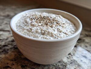 Close-up of creamy chia seed pudding topped with seeds in a white bowl.