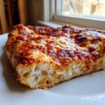 Close-up of a thick slice of pizza showing the airy interior of the cottage cheese pizza crust topped with melted cheese and sauce.