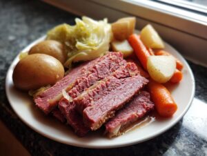 A plate featuring tender sliced corned beef served with boiled potatoes, carrots, and cabbage.