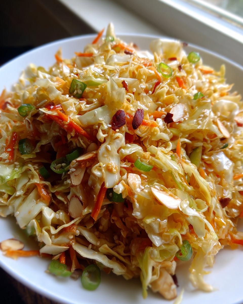 Close-up of a vibrant asian ramen noodle salad with cabbage, carrots, almonds, and sesame seeds.