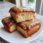 Three stacked pieces of moist buttermilk donut bars topped with a thick, glossy caramel-colored glaze.