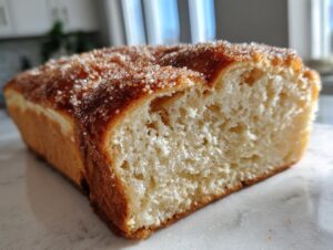 A close-up cross-section of freshly baked cinnamon sugar bread showing the soft interior and sparkling cinnamon sugar topping.
