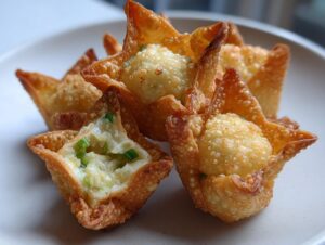 Close-up of crispy, golden homemade crab rangoons, one of which is cut open showing the creamy filling and green onions.