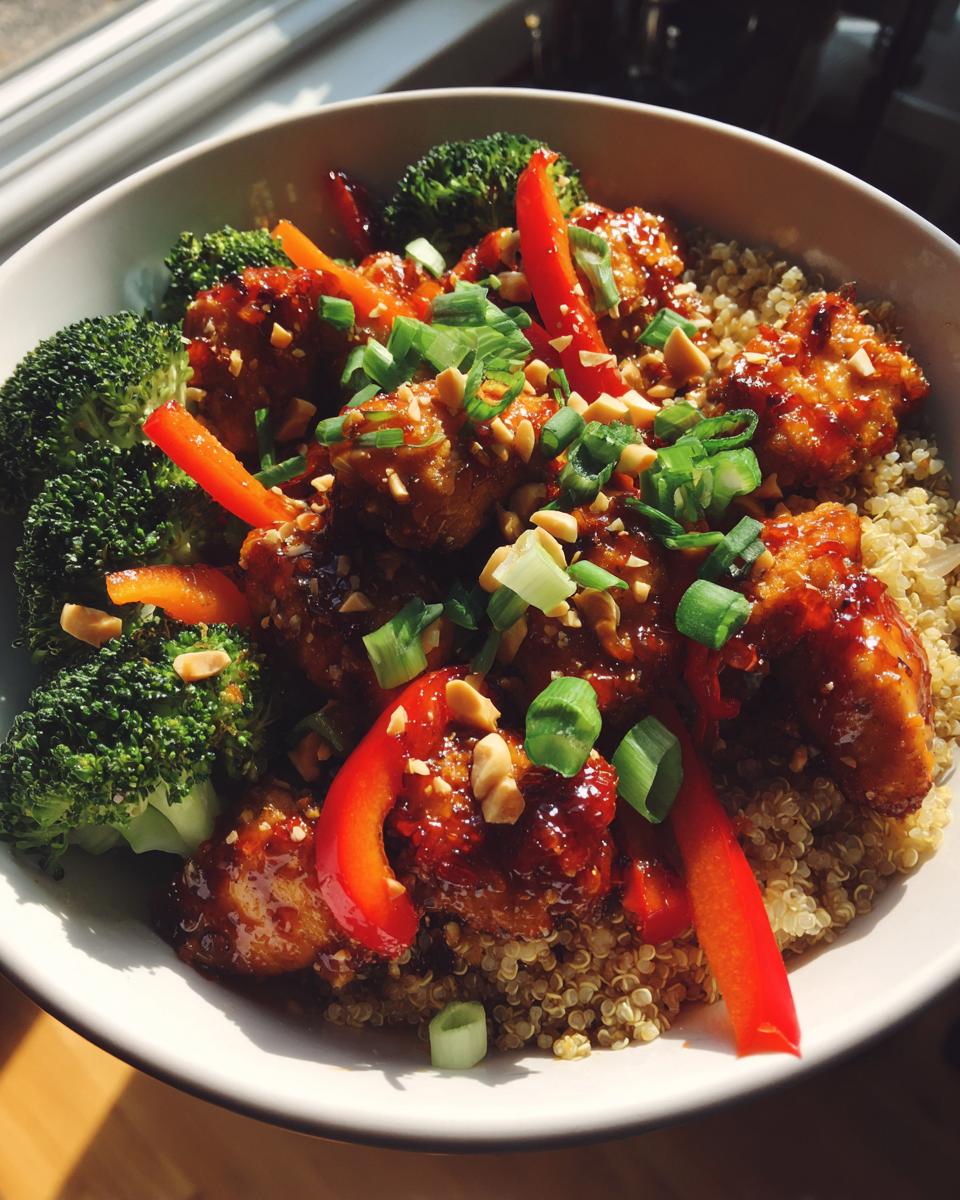 Close-up of a high-protein peanut chicken meal prep bowl featuring glazed chicken, quinoa, broccoli, and red peppers.