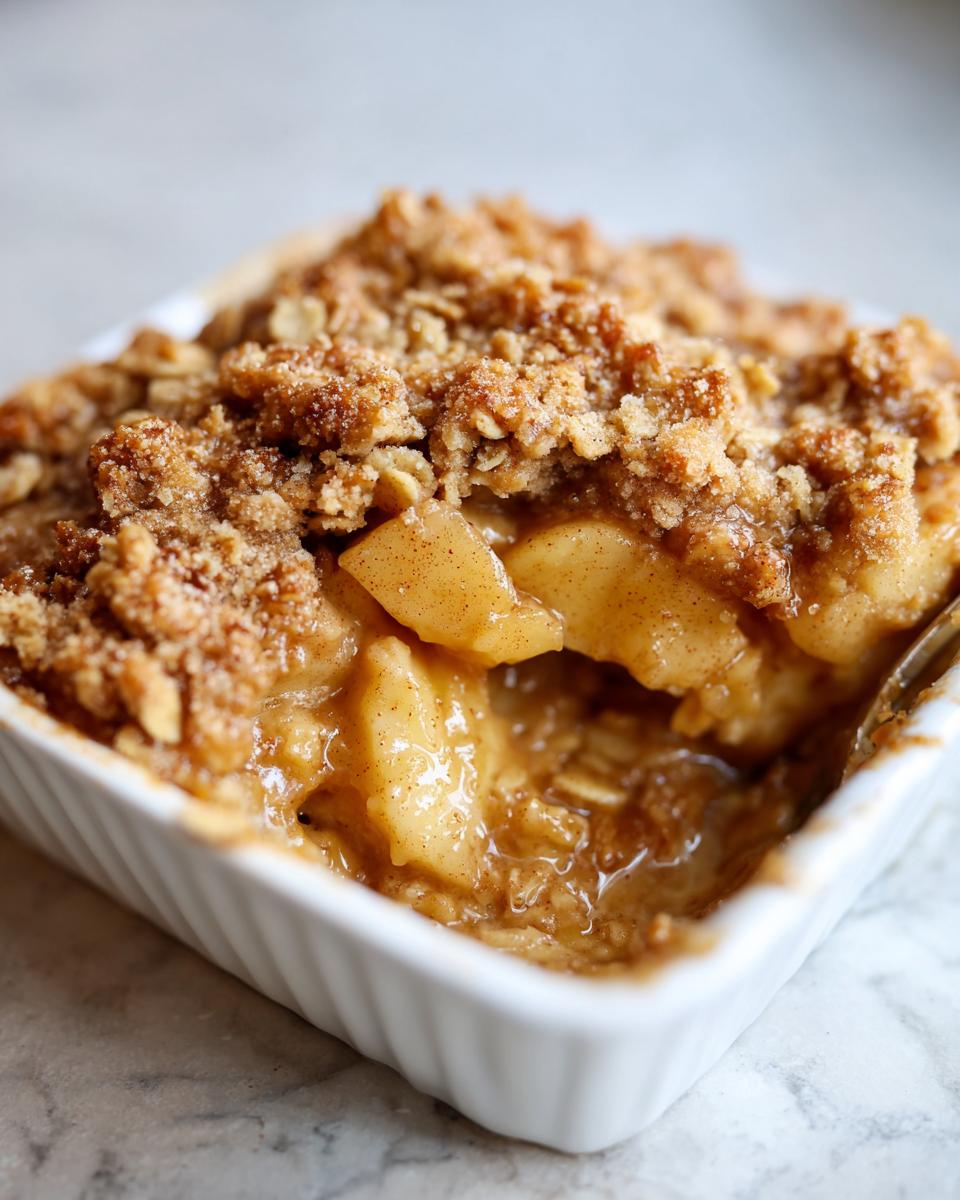 A close-up of a single serving of warm cinnamon apple crisps in a white ramekin, showing gooey apples and crunchy topping.