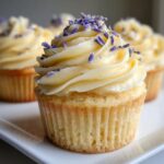 A close-up of a beautifully frosted lavender honey cupcake topped with dried lavender buds.