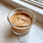 Close-up of creamy Lebanese date blossom mousse swirled in a small clear glass cup.