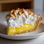 Close-up of a perfect slice of lemon cream pie recipe with bright yellow filling and toasted meringue topping.