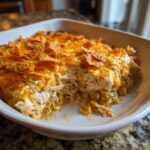 A scoop has been taken out of a cheesy Mexican chicken casserole topped with crushed tortilla chips.