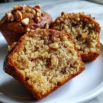 Close-up of a moist banana nut muffins cut in half showing the texture and nuts inside.