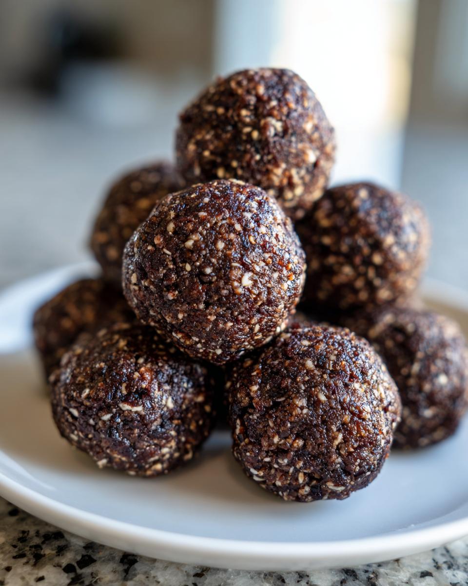 Close-up of a small stack of rich, dark no bake hazelnut cacao bites on a white plate.
