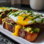 Close-up of prime rib and eggs avocado toast with a runny yolk dripping down the side.