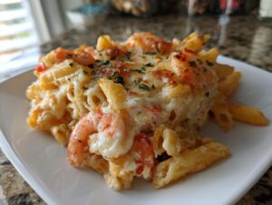 A close-up serving of creamy shrimp scampi pasta bake topped with melted, slightly browned cheese and parsley.