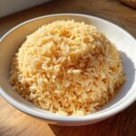 A close-up of fluffy, golden brown texas roadhouse seasoned rice mounded in a white bowl.