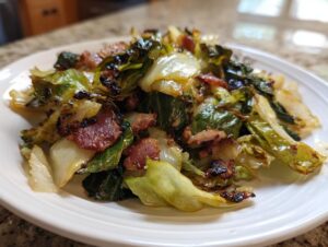 A close-up of delicious fried cabbage mixed with crispy bacon pieces served on a white plate.