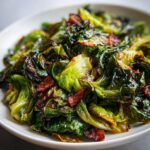 A close-up of delicious fried cabbage mixed with crispy bacon pieces served in a white bowl.