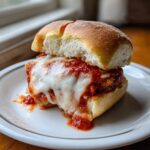 Close-up of a delicious chicken parmesan sliders sandwich with melted mozzarella cheese dripping over marinara sauce.