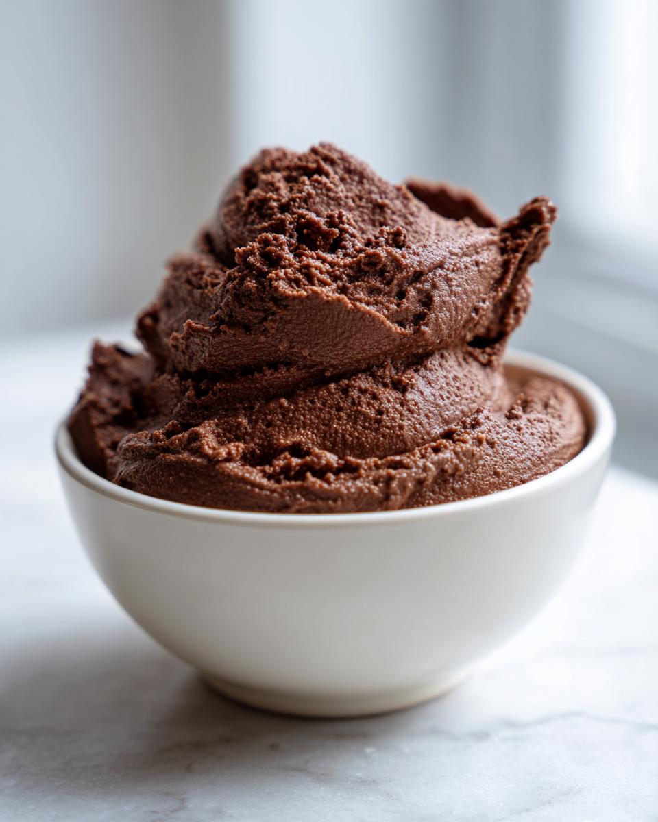 A generous scoop of rich, dark chocolate cottage cheese mousse piled high in a small white bowl.