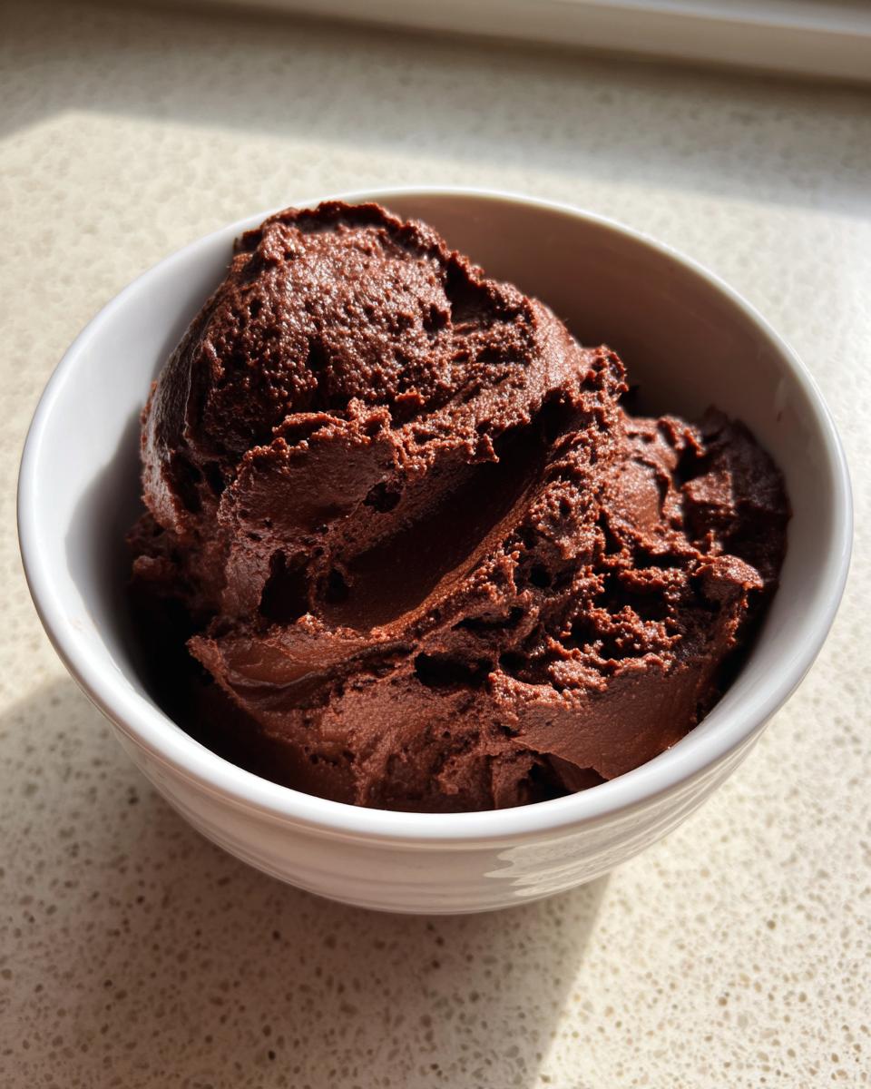 A scoop of rich, dark chocolate cottage cheese mousse served in a small white bowl.