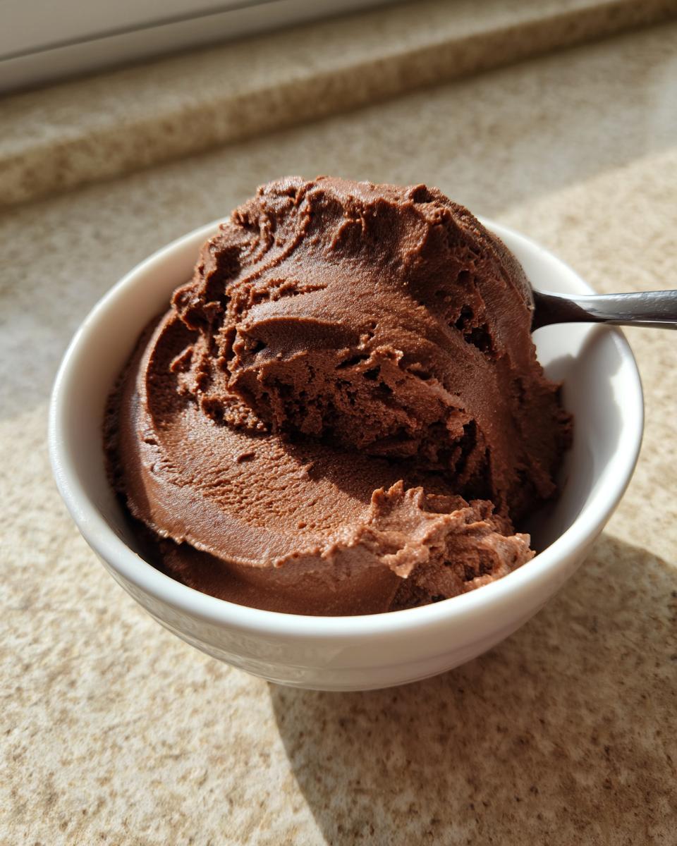 A scoop of rich, dark chocolate cottage cheese mousse served in a small white bowl.
