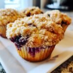 Close-up of a fluffy Blueberry lemon muffins topped with golden brown streusel.