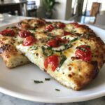 Two slices of freshly baked Margherita flatbread topped with melted mozzarella, roasted cherry tomatoes, and fresh basil.