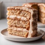 Close-up of a tall slice of Snickerdoodle cake with layers of cinnamon filling and cream cheese frosting.