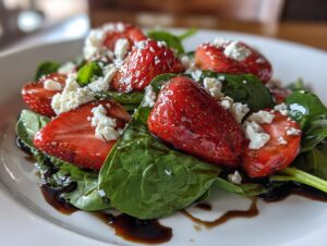 Close-up of a vibrant Strawberry Balsamic Salad featuring sliced strawberries, spinach, feta cheese, and balsamic glaze.
